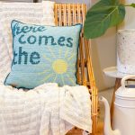 Detailbeeld van geborduurde tekst Here comes the